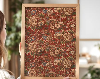 May include: A framed floral print featuring a detailed pattern of cream, blue, and green flowers and foliage on a deep red background. The wooden frame has a natural finish. The print is held by a person.
