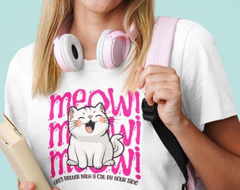 May include: White t-shirt with a pink graphic of a cat and the words "meow!" repeated three times. The text "Life's better with a cat by your side" is below the cat illustration. The person is wearing pink headphones and carrying a pink backpack.