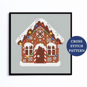 Könnte beinhalten: Ein Kreuzstichmuster eines Lebkuchenhauses mit schneebedecktem Dach, verziert mit bunten Lichtern und Schneeflocken. Das Haus hat zwei Fenster, eine Tür und den Text "CROSS STITCH PATTERN" in einem blauen Kreis.