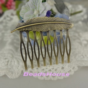 May include: A gold-toned hair comb with a feather design. The comb has seven teeth and is decorated with a detailed feather design.