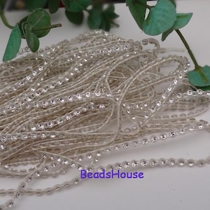 Puede incluir: Una bobina de ribete de strass transparente con un borde de cuentas. El ribete está hecho de pequeños strass transparentes cosidos sobre un hilo transparente. El ribete es perfecto para agregar un toque de brillo a cualquier proyecto.