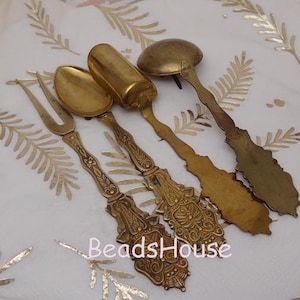 May include: Set of four ornate gold-toned metal serving utensils. The set includes a fork, two spoons, and a small scoop.