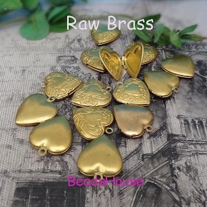 May include: A collection of 12 raw brass heart-shaped locket charms with intricate designs. The lockets are open and ready to be filled with your favorite trinkets or photos.