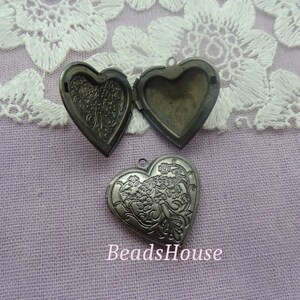 Puede incluir: Tres colgantes de corazón de plata con un diseño floral adornado. Los colgantes están abiertos para revelar el interior.