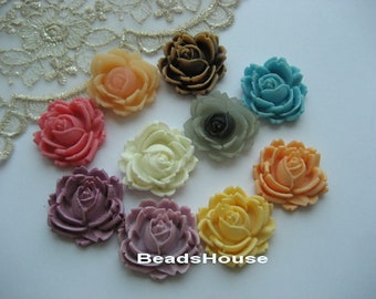 May include: Assortment of ten resin flower embellishments in various colors, including pink, purple, cream, yellow, blue, gray, and brown. The flowers are all approximately the same size and have a raised, three-dimensional design.