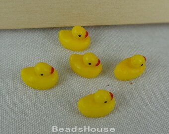 May include: Five small yellow rubber duck toys with red beaks. The ducks are arranged in a semi-circle on a white surface.
