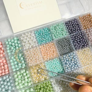 Peut inclure: Un organisateur en plastique transparent rempli de perles de diff&eacute;rentes couleurs. Les perles sont dans des tons de rose, de vert, de bleu et de cr&egrave;me. Le texte "CELESTIAL BEADS & CRAFTS" est visible en haut &agrave; gauche. Le texte "Beads not included, for Demo only" est en bas.