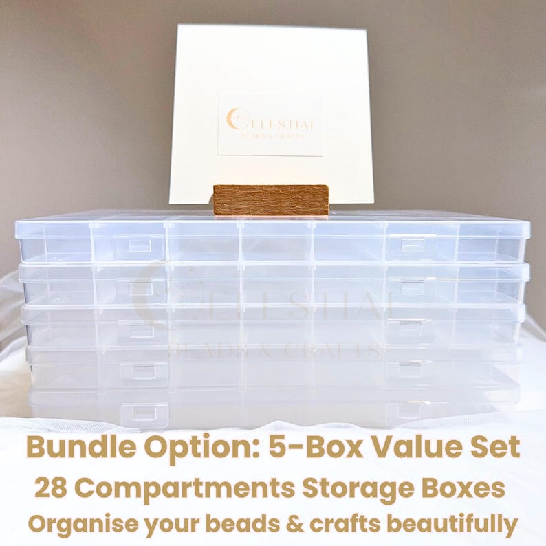 Peut inclure: Ensemble de cinq bo&icirc;tes de rangement en plastique transparent avec plusieurs compartiments. L'ensemble est pr&eacute;sent&eacute; comme un lot de 5 bo&icirc;tes avec 28 compartiments, pour organiser perles et travaux manuels. Une carte blanche et un bloc de bois sont derri&egrave;re.