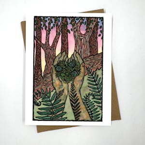 Może przedstawiać: Kartka okolicznościowa z akwarelową ilustracją dłoni trzymających skupisko zielonych roślin w kształcie serca. Tło przedstawia scenę leśną z drzewami i różowo-fioletowym niebem. Paprocie są na pierwszym planie. Karta jest na białym tle z brązową kopertą.