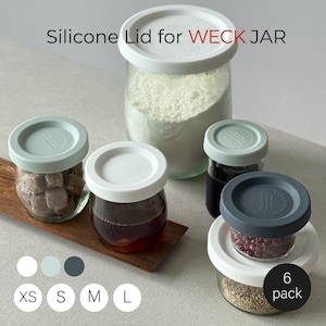 以下が含まれることがあります： 様々な食材が入った、白と水色のシリコン蓋付きガラス瓶のコレクション。「Silicone Lid for WECK JAR」の文字が上部に表示されています。「6 pack」のステッカーが見えます。