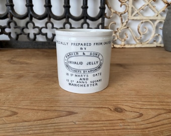 May include: A white ceramic jar with a cylindrical shape, featuring a blue and black label that reads "INVALID JELLY" and "PARKER & SONS." The jar has text that reads "18 ST MARYS GATE AND 12 ST ANNS SQUARE MANCHESTER."