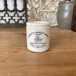 May include: White ceramic jar with black lettering that reads "Cooperative Wholesale Society Limited Grocery Productive Dept Silvertown, London" and "Extract of Meat".