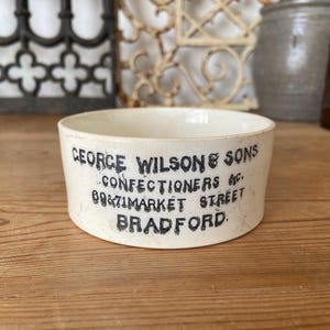 May include: White ceramic bowl with black lettering that reads "George Wilson & Sons Confectioners 69 & 71 Market Street Bradford".