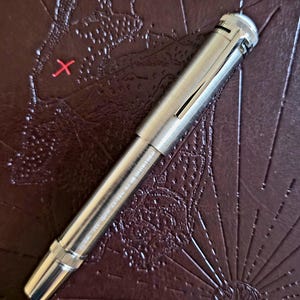 Peut inclure: Une tasse en c&eacute;ramique blanche avec une anse noire et le texte "But First, Coffee" en gras noir. La tasse est pos&eacute;e sur un fond flou, sugg&eacute;rant un cadre chaleureux.