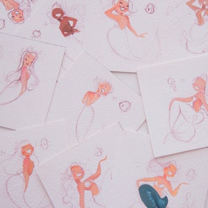 Puede incluir: Una colecci&oacute;n de ocho acuarelas de sirenas en papel blanco. Las sirenas est&aacute;n dibujadas en un estilo caprichoso con acentos rosas y rojos.