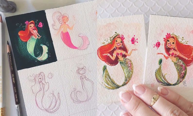 Puede incluir: Una colecci&oacute;n de pinturas de acuarela con sirenas de pelo rojo y colas verdes. Las sirenas est&aacute;n rodeadas de flores rosas y blancas y burbujas. Las pinturas est&aacute;n en peque&ntilde;os cuadrados blancos.