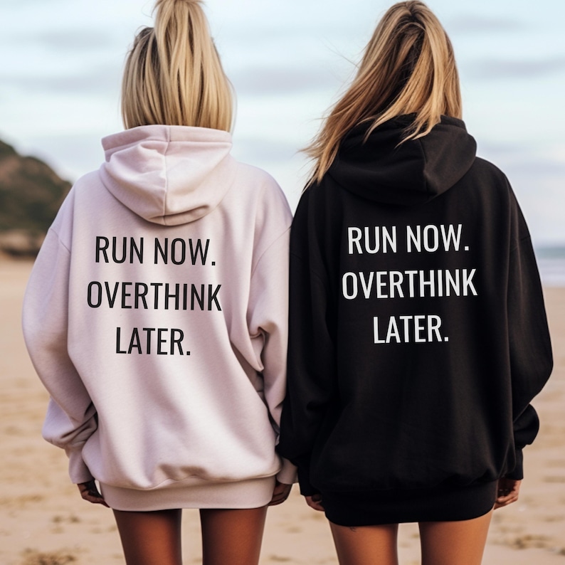 May include: Two hooded sweatshirts, one light pink and one black, with the text "RUN NOW. OVERTHINK LATER." printed in white on the back. The sweatshirts are worn by two people standing on a beach.