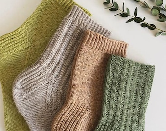 May include: Four pairs of knitted socks in different colors: green, beige, brown, and light green. The socks are folded and arranged on a white surface.