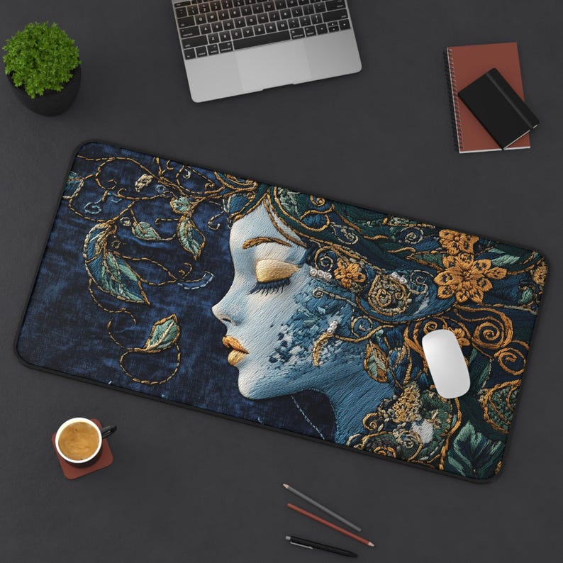 May include: A blue and gold embroidered mouse pad with a detailed image of a woman's face with her eyes closed. The woman's hair is flowing and decorated with gold flowers.
