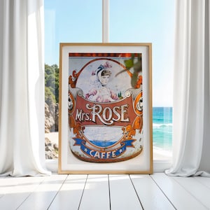 May include: A vintage tin can with a colorful design featuring a woman in a pink dress and the text "Mrs. Rose Caffe".