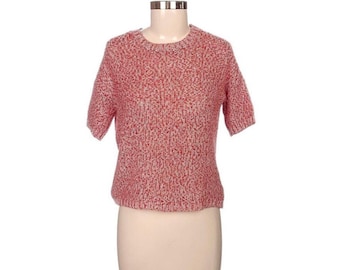 May include: A short-sleeved, crew-neck sweater in a speckled red and white knit fabric. The sweater is displayed on a mannequin, showcasing its textured appearance and casual style. The garment's design features a classic round neckline and short sleeves.