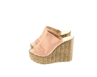 Op de afbeelding: Een paar lichtroze suède sleehak sandalen. De open teen schoenen hebben een kurken platform en sleehak. De sandalen zijn elegant en stijlvol, perfect voor een zomerse look.
