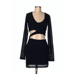 May include: Black two-piece dress with long mesh sleeves and a cutout design. The top has a V-neck and a crisscross detail at the midriff. The skirt is a mini length. The dress is displayed on a mannequin.
