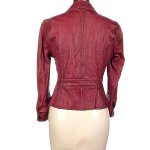 Op de afbeelding: Bordeaux leren jas met een getailleerde pasvorm, met een reverskraag en manchetten met knopen. De achterkant toont een gestructureerd ontwerp met een taille detail, wat een klassieke en stijlvolle buitenkleding optie biedt.