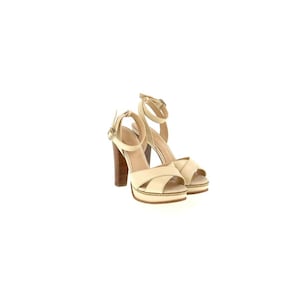 May include: A pair of cream-colored platform sandals with crisscross straps and ankle straps. The sandals have wooden block heels and gold-colored accents. The heels are approximately 4 inches (10 cm) high.