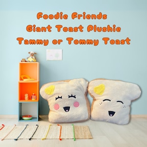 May include: Two large plush toys shaped like slices of toast with smiling faces. The toast is white with a yellow butter pat on top. The text "Foodie Friends Giant Toast Plushie Tammy or Tommy Toast" is written in orange letters on a light blue wall.