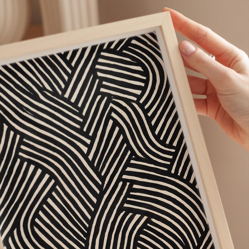 Black and white abstract line art poster featuring bold geometric striped patterns woven into a modern minimalist design on a beige background.
