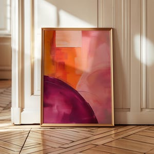 Op de afbeelding: Abstracte kunstprint in een gouden lijst met roze, oranje en paarse kleuren. De print bevat geometrische vormen en penseelstreken.