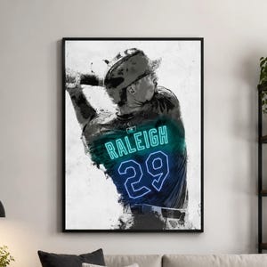 May include: A framed wall art print featuring a black and white watercolor-style illustration of a baseball player swinging a bat. The player wears a jersey with the name RALEIGH and the number 29 in glowing neon blue text across the back.