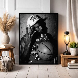 A framed black and white photograph of a basketball player, likely Michael Jordan, holding a basketball and making a peace sign gesture.
