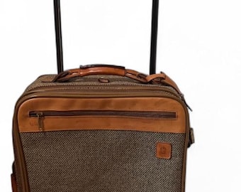 May include: Brown and tan rolling suitcase with a retractable handle. The suitcase has a textured fabric body with leather accents, a front zipper pocket, and a top handle. The handle extends to a height of approximately 40 inches.