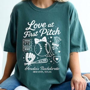 Peut inclure: T-shirt vert d'eau avec l'inscription "Love at First Pitch" et des graphiques sur le thème du baseball. Le motif comprend une balle de baseball, un gant et une date. Le texte "Amelia's Bachelorette, Houston, Texas" est également imprimé.