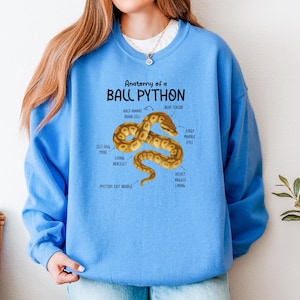 Könnte beinhalten: Hellblaues Sweatshirt mit dem Text "Anatomy of a BALL PYTHON" und einer Abbildung einer Schlange. Die Schlange ist braun und beige mit beschrifteten Teilen. Das Sweatshirt ist einfarbig hellblau, ein lässiges und bequemes Kleidungsstück.