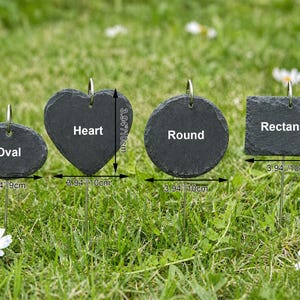 May include: Four dark gray slate garden markers in oval, heart, round, and rectangular shapes, each with a metal loop for hanging. The oval is 3.54 inches wide, the heart and round are 3.94 inches wide, and the rectangle is 3.94 inches wide.