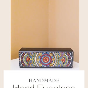 Könnte beinhalten: Handgefertigte harte Brillenhülle mit einem farbenfrohen Mosaikdesign. Die Hülle ist schwarz mit einem bunten Muster aus Kreisen und Punkten.