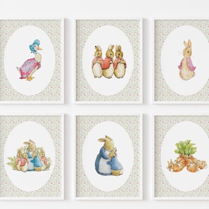 May include: Six framed art prints featuring watercolor illustrations of Beatrix Potter characters. The prints include images of a duck, rabbits, and carrots, set against a floral patterned background. The artwork is displayed in white frames.