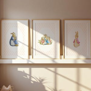 Pode incluir: Três impressões em aquarela emolduradas com personagens de Peter Rabbit. As impressões têm um fundo de bolinhas rosa claro. Uma impressão mostra um coelho com um vestido azul abraçando um coelho menor. Outra mostra um grupo de coelhos. A terceira impressão mostra um coelho com uma jaqueta rosa.