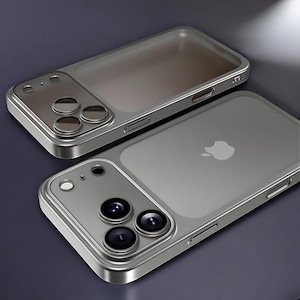 May include: Two silver-colored phone cases. The cases have a transparent back with the Apple logo and a silver frame. Each case has a camera module with three lenses. The cases are designed to protect the phone.