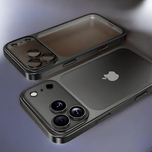 May include: Two black phone cases with a transparent back and camera lens cutouts. One case is positioned above the other, showcasing the design. The Apple logo is visible on the back of one case.
