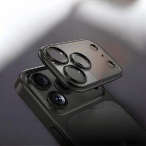 May include: A black smartphone with a protective camera lens cover. The cover is transparent with black circular lens protectors. The phone's camera lenses are visible beneath the cover. The phone and cover are set against a gradient background.