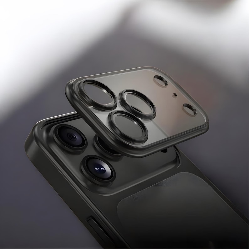 May include: A black smartphone with a protective camera lens cover. The cover is transparent with black circular lens protectors. The phone's camera lenses are visible beneath the cover. The phone and cover are set against a gradient background.