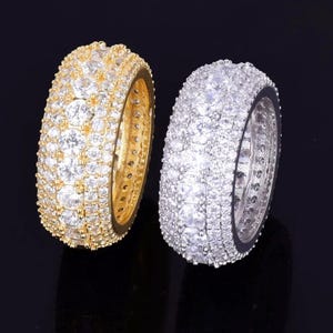 May include: Two gold and silver rings with multiple rows of clear cubic zirconia stones.