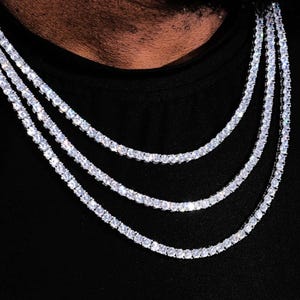 May include: Three layered silver chain necklaces with clear cubic zirconia stones.
