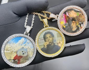 May include: Three gold, silver and rose gold pendants with a round photo frame design. Each pendant has a different photo inside the frame. The pendants are on a rope chain.