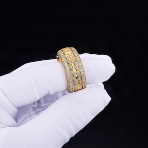 Peut inclure: Une bague en or avec une bande épaisse et un design serti de diamants. La bague présente un motif tressé avec plusieurs rangées de petits diamants.