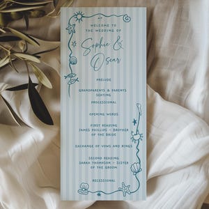 May include: A white ceramic mug with a black handle and the text "But First, Coffee" in a bold, black font. The mug is set against a blurred background, suggesting a cozy setting.